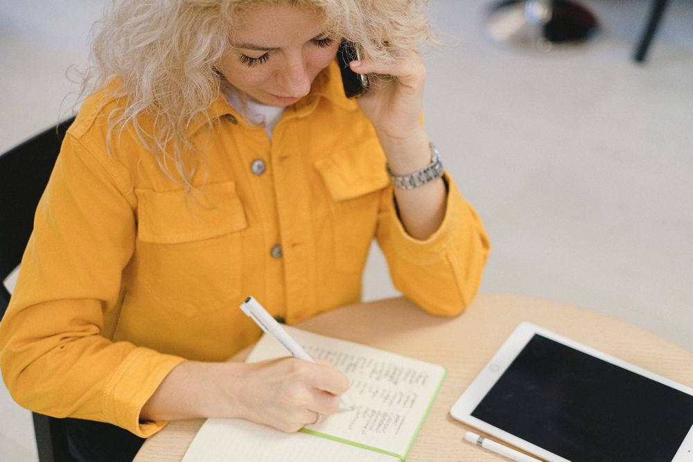 Person taking notes during a phone conversation