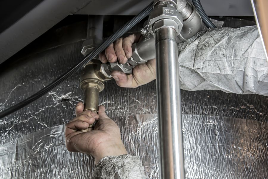 Plumber fitting a pipe beneath a sink